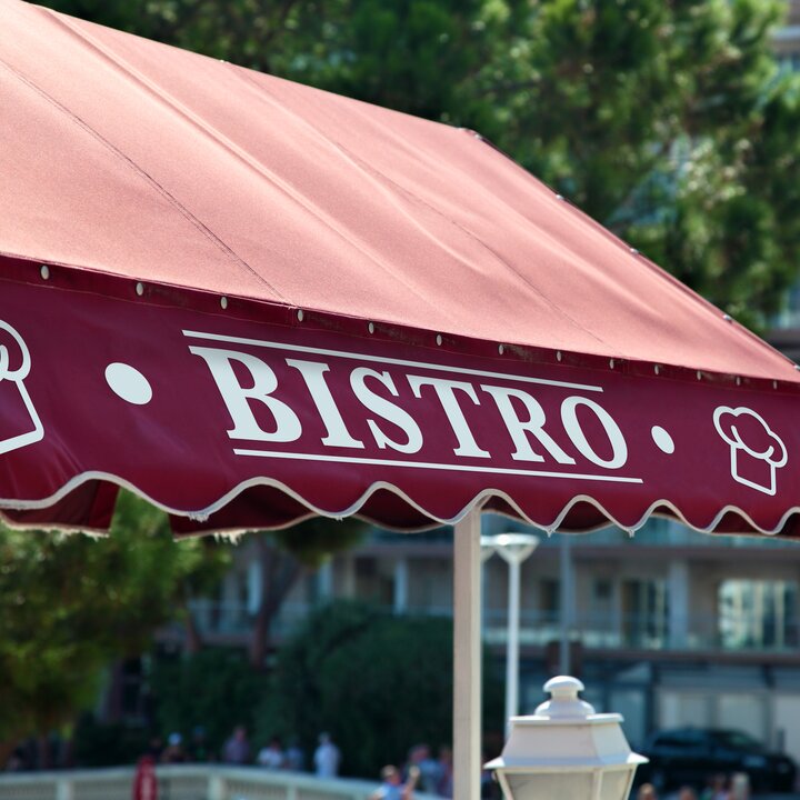 An awning adorned with crisp signage vinyl lettering, displaying the name or logo of a business, providing both shade and a distinctive visual identity to the storefront. | © Orafol